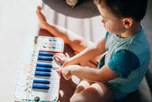 Top View Of A Baby Boy Sitting On Floor And Playing With A Plastic Toy Music Piano. Colorful Toy.