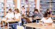 © JackF - Focused schoolchildren, engaged in lessons in the school library, write a summary from textbooks and study new material