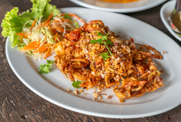 Wall Mural - Close up Thai food image, deep-fried soft shell crab with garlic on wooden table, crispy deep-fried soft shell crab with garlic. 45-degree angle view.