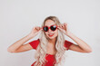 © Natalya - Adorable young blonde girl in red bodysuit and glasses in the shape of hearts posing on white background