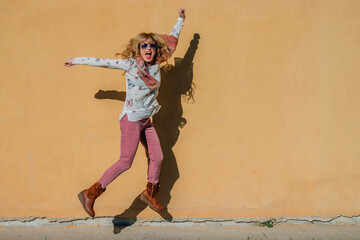 woman jumping for joy with outdoor wall background