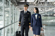 © Kawee - Asian airliner pilot and air hostess walk together in airport terminal