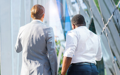 Wall Mural - Finance, business and cooperation concept. Two successful businessmen are talking on the street. Office workers are discussing business issues outdoor.