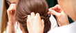 © okskukuruza - A hairdresser is making the hairstyle of a young brunette woman in a hair salon, close up