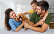 © NDABCREATIVITY - Happy family having fun time, playing together at home with dog
