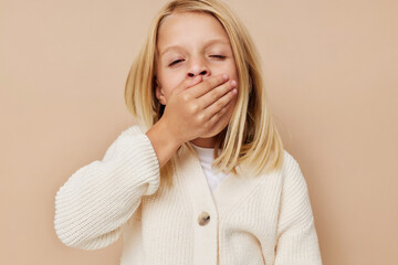 Wall Mural - Beautiful little girl in a white sweater on a beige background