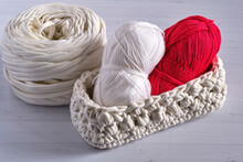 Large Skein Of Yarn For Knitting, Knitted Basket With Two Skeins Of Yarn For Knitting: Red And White, On A Light Background