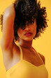 © Carlos David - portrait of beautiful young African american woman in bright summer outfit posing isolated on yellow background
