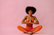 © Carlos David - beautiful African american woman meditating in sports outfit on pink background