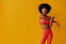 Attractive Young Adult Fit African American Woman In Sportswear Stretching Isolated On Orange Background