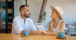 © South House Studio - Loving couple sit at a table in open cafe holding hands man braking up with woman