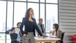 © Ron - A young female manager in smart casual dress stands in arm crossed in front of other colleagues with confident to express ambitious target of their business strategy or plan. Young female executive