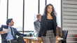 A young female manager in smart casual dress stands in arm crossed in front of other colleagues with confident to express ambitious target of their business strategy or plan. Young female executive
