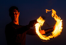 Game Of Light And Dark. Fire Spinner At Night. Happy Male Spinner Spin Burning Poi.