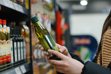 Female hand choosing natural olive oil at store. Concept of healthy food, bio, vegetarian, diet.