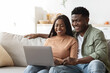 © Prostock-studio - Relaxed african american young couple enjoying weekend together, using laptop