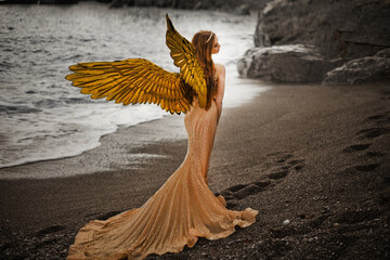 Young beautiful woman fallen angel stands on sea beach enjoy nature. costume bird white wings.