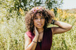 © Cavan Images - Woman looks into camera while sitting in field of wild flowers