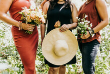 Close Up Of  Group Of Women Holding Flowers And Large Sun Hat