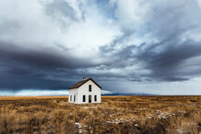 Storm Clouds Loom Over White Abandoned House In Desert, Colorado