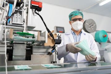 Wall Mural - male factory worker are producing medical face masks, counting and checking of quality from machine