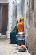 Muslim woman cooking and speaking in the phone outdoors in the street of Stone Town, Zanzibar, Tanzania