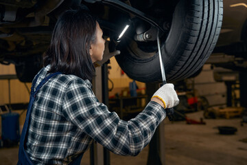 Wall Mural - Focused female car technician fixing a tyre