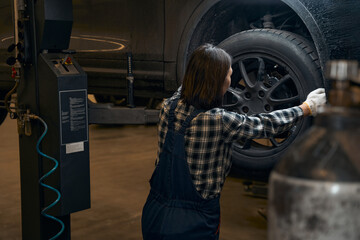 Wall Mural - Qualified female mechanic replacing a tyre on a car