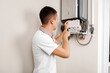 © Ruslan Ivantsov - Plumber attaches Trying To Fix the Problem with the Residential Heating Equipment. Repair of a gas boiler