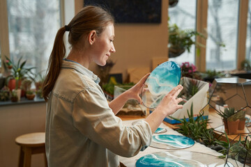 Smiling woman holding beautiful art in the workshop