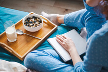 Woman Writes In Large White Open Notebook, Sitting On Bed In Blue Pajamas With Breakfast With Oatmeal. Top View. Morning Routine. Healthy Lifestyle. Morning
