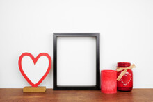 Mock Up Black Frame With Valentines Day Heart Decor And Candles. Wood Shelf Against A White Wall. Copy Space.