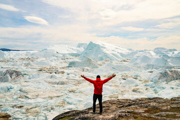 Wall Mural - climate change and global warming optimism and positivity concept. man on greenland arms raised in a