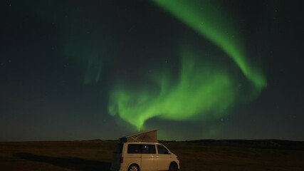 Wall Mural - A stunning dance of the bright northern light in the starry night sky above the small white van with a popped-up tent