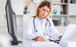 Leinwandbild Motiv positive female doctor with stethoscope working in cabinet