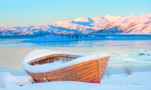 Orange Wooden Boat Covered With Layers Of Snow At Sunset - Cracks On The Surface Of The  Ice - Tromso, Norway
