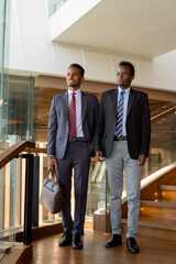 Wall Mural - Two African businessman wearing suit and tie at coffee shop full length shot