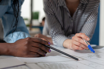 Poster - Closeup of architectural engineer hands holding pencil and pen over blueprints at modern technical drawing desk. Detailed view of architects inspecting construction plans of residential project.