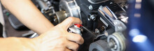 Master Locksmith Puffs Liquid On Motorcycle Engine In Garage Closeup
