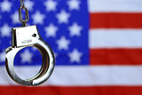 Fototapeta Krajobraz - handcuffs on the background of the US flag, the concept of crime in the United States of America, selective focus