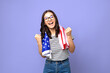© Andrei - very excited attractive brunette in striped t-shirt with usa flag against a purple background