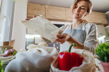 Wall Mural - Young woman holding the organic cotton reusable produce bag with vegetables