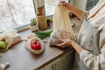 Wall Mural - Young woman holding the organic cotton reusable produce bag with vegetables and fruits