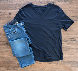 Wall Mural - Blue T-shirt and jeans mock up flat lay on wooden background. Top view