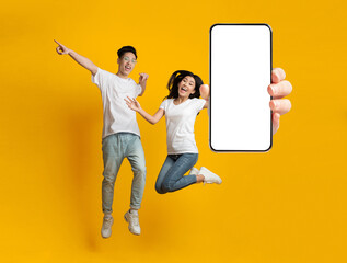 Asian couple showing white empty smartphone screen and jumping