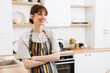 © Drobot Dean - White young woman wearing apron smiling while standing in kitchen