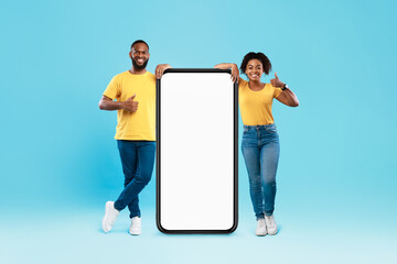 Poster - Young African American couple standing near giant smartphone with mockup, showing thumbs up