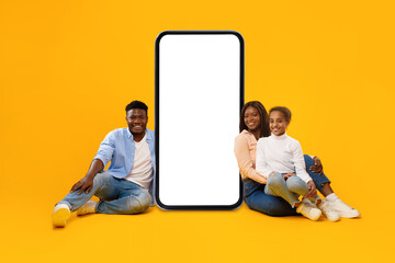 Black family showing white empty smartphone screen leaning on display