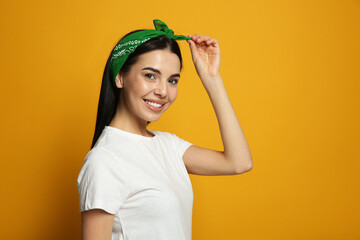 Wall Mural - Young woman wearing stylish bandana on orange background, space for text