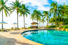 Beautiful Luxury Umbrella And Chair Around Outdoor Swimming Pool In Hotel And Resort With Coconut Palm Tree On Blue Sky